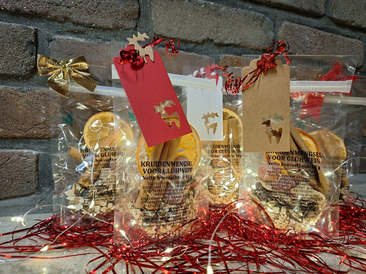 Drie zakjes glühwein kruiden met cadeaulabels en gedroogde sinaasappel, klaar als kerstcadeau